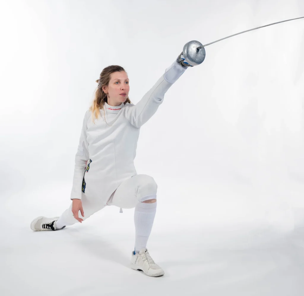 Auriane Mallo en fente basse, épée tendue, sur fond blanc