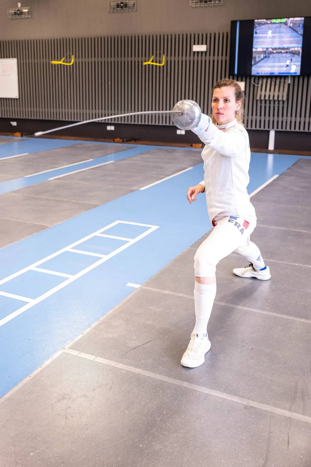 Auriane Mallo en fente dans la salle d'armes, lumière naturelle