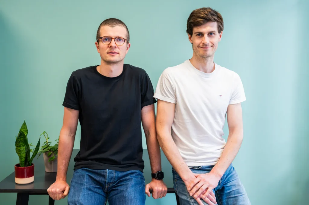 Portrait de deux membres de l'équipe FYGR posant côte à côte devant un mur turquoise