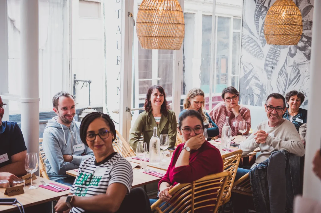 Convives attablés qui sourient lors du déjeuner HomeExchange