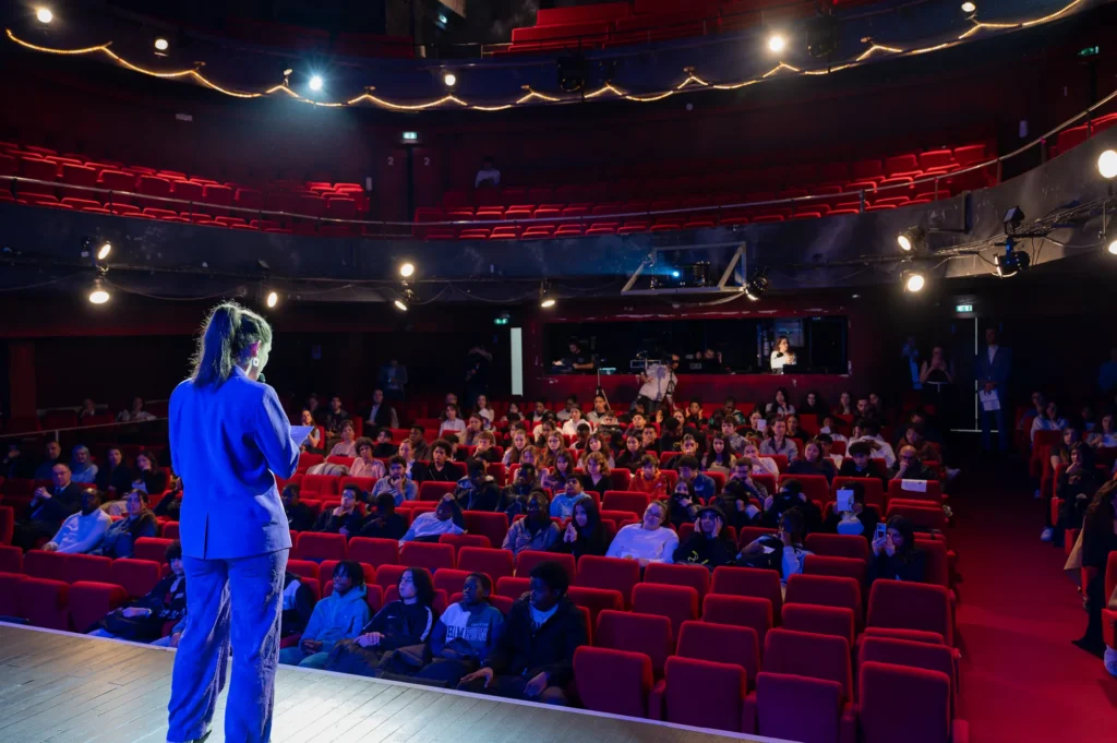 Intervenante sur scène devant le public du théâtre lors du festival Les collégiens ont la parole