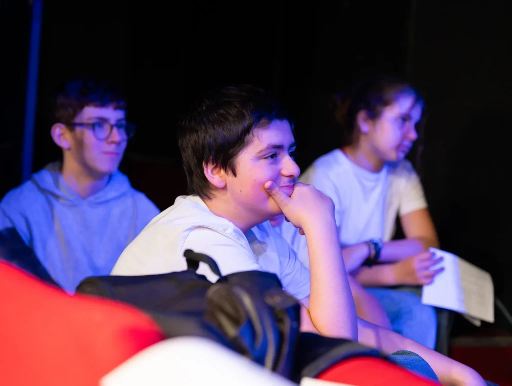 Trois collégiens souriants dans le public du festival Les collégiens ont la parole