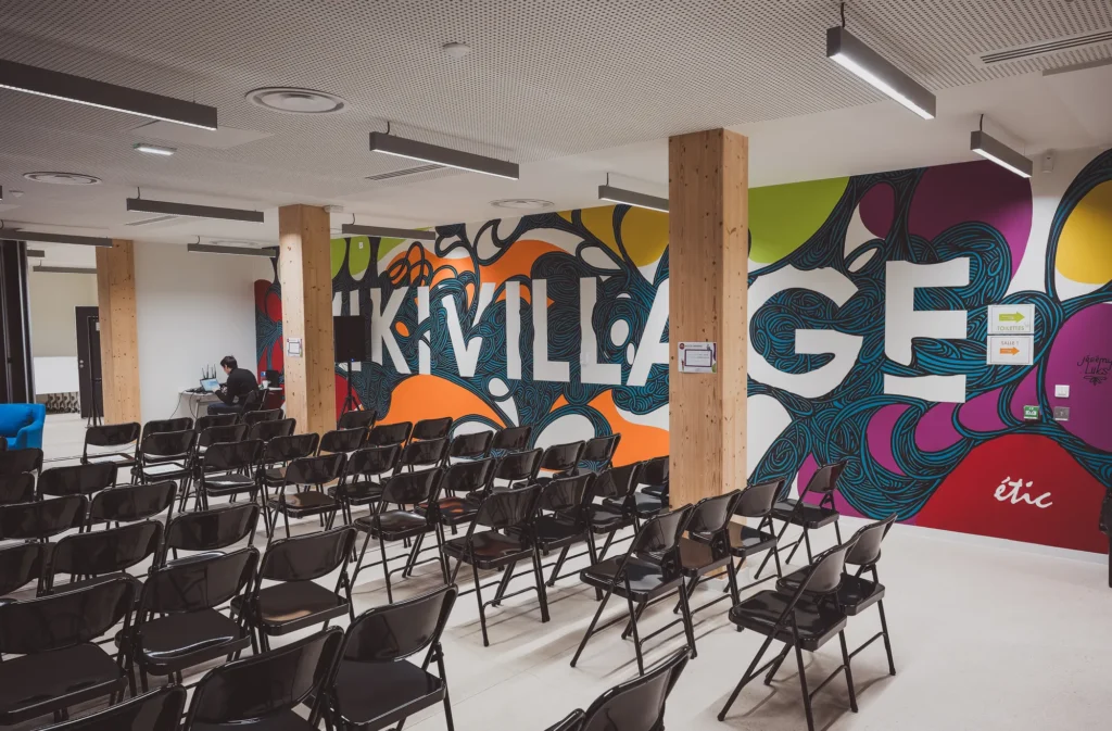 Salle aménagée pour l'inauguration du Wikivillage, devant une fresque colorée