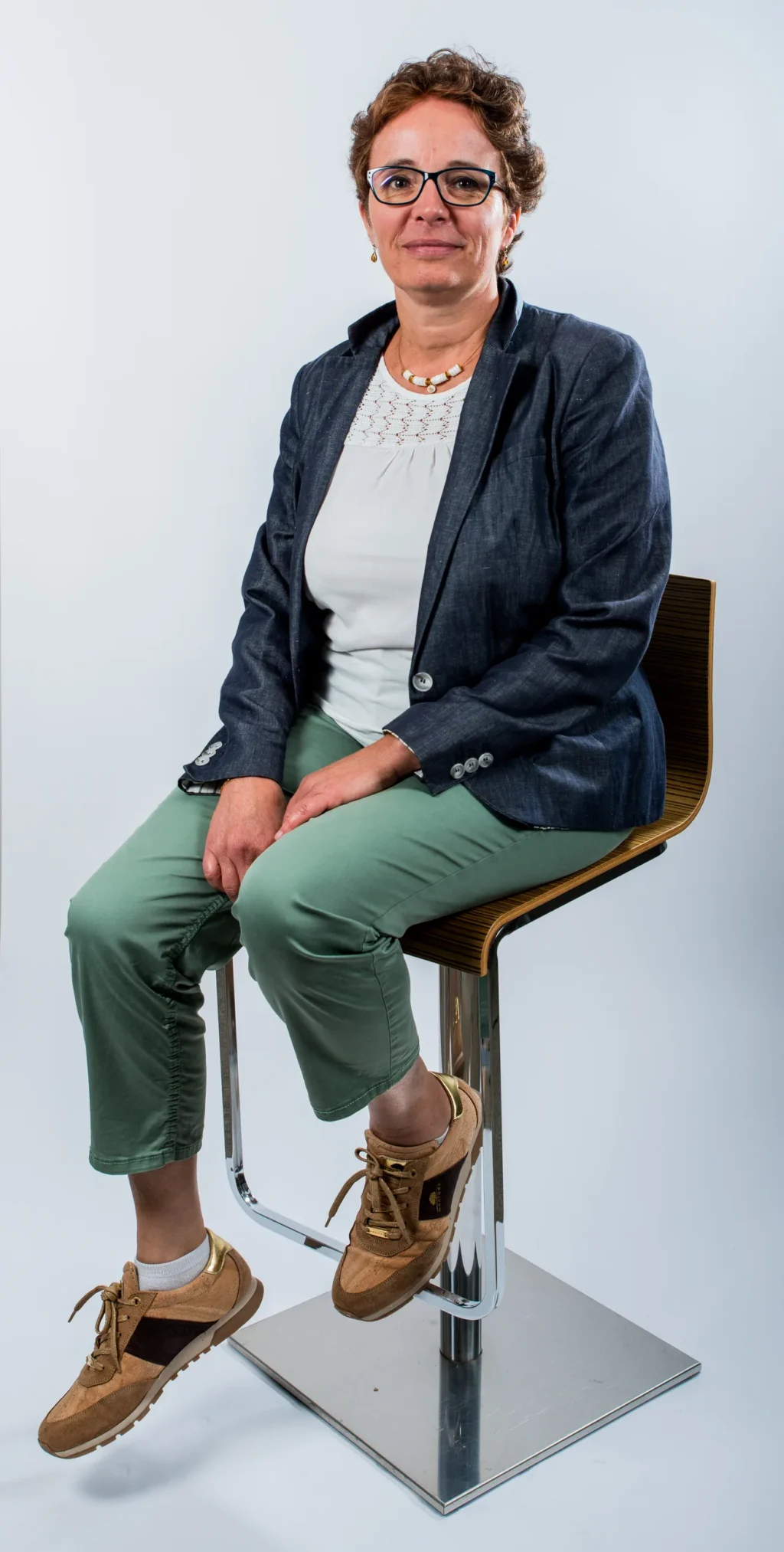 Portrait corporate d'un membre de l'équipe Yabuko en blazer et pantalon vert, assis sur un tabouret